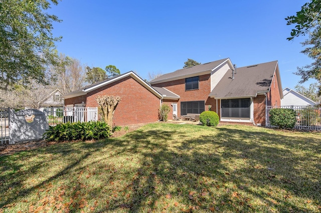 rear view of property with brick siding, a lawn, and fence