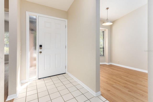 foyer entrance with a healthy amount of sunlight, baseboards, and light tile patterned floors