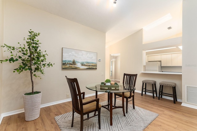 dining area with light wood finished floors, visible vents, and baseboards