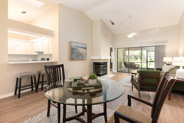 living area featuring visible vents, baseboards, a ceiling fan, a tiled fireplace, and light wood-style flooring