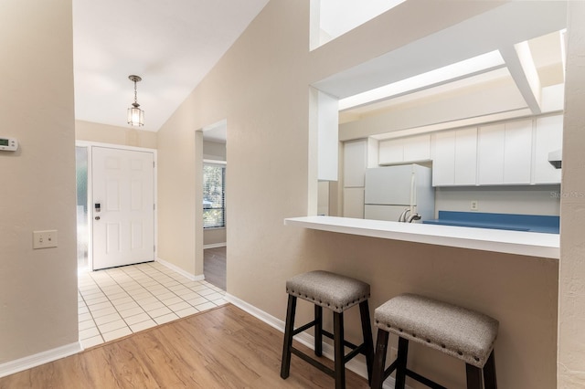 foyer entrance with vaulted ceiling, light wood finished floors, and baseboards