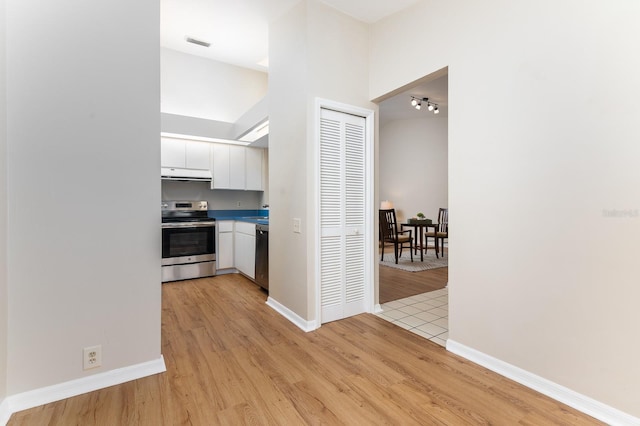 hall featuring baseboards, visible vents, and light wood-style floors