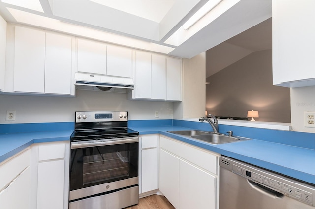 kitchen with appliances with stainless steel finishes, white cabinets, a sink, and under cabinet range hood