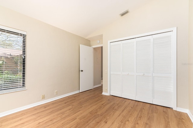 unfurnished bedroom with visible vents, baseboards, vaulted ceiling, a closet, and light wood finished floors