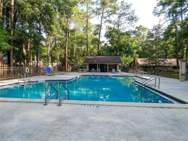 community pool featuring a patio area, fence, and an outbuilding