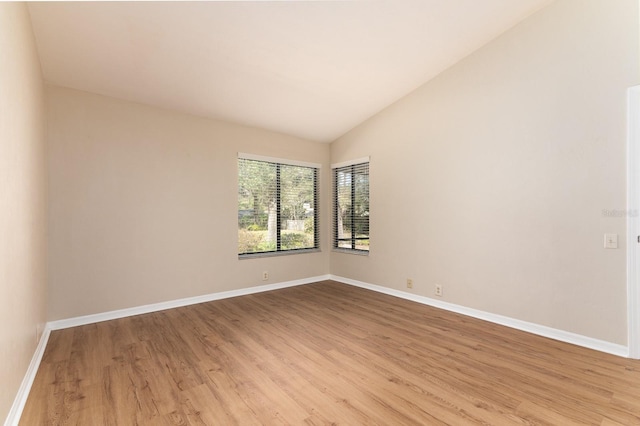 unfurnished room featuring lofted ceiling, light wood-style flooring, and baseboards