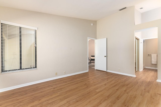 unfurnished bedroom featuring high vaulted ceiling, light wood finished floors, visible vents, and baseboards