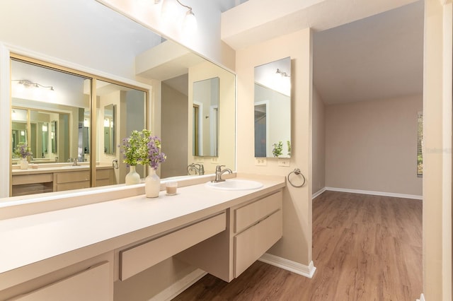 bathroom with wood finished floors, vanity, and baseboards