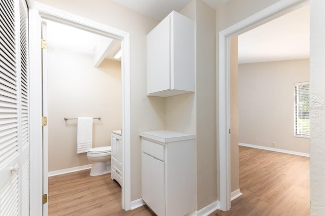 bathroom with baseboards, vanity, toilet, and wood finished floors