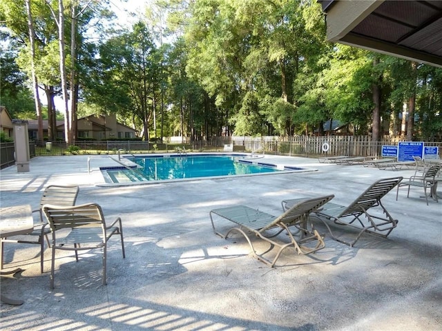 pool with a patio area and fence