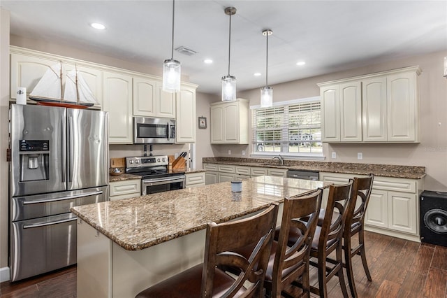 kitchen featuring visible vents, appliances with stainless steel finishes, dark wood-style flooring, a center island, and a sink