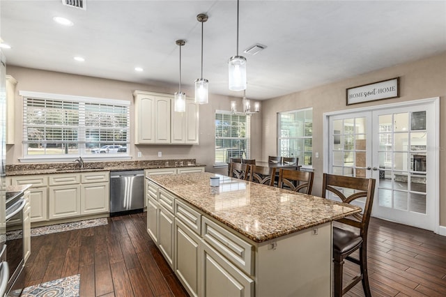 kitchen featuring light stone counters, a center island, pendant lighting, visible vents, and stainless steel dishwasher