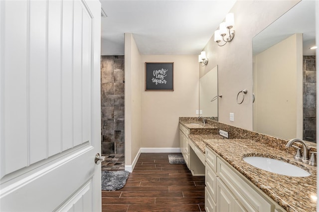 bathroom featuring double vanity, baseboards, a sink, and wood finish floors