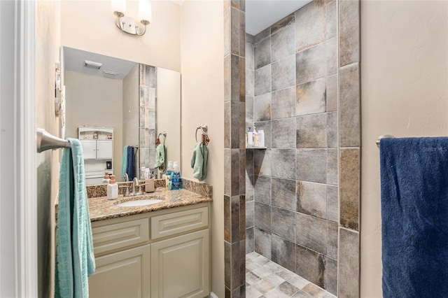 bathroom with a tile shower and vanity