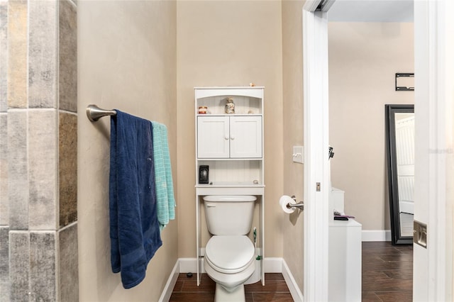 bathroom with toilet, baseboards, and wood finished floors