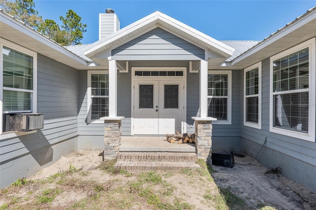 entrance to property featuring covered porch, metal roof, and a chimney