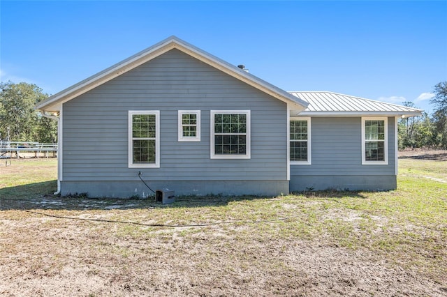 view of side of home with fence, metal roof, and a yard