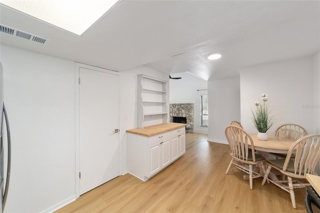 dining room with light wood-style floors, visible vents, a fireplace, and baseboards