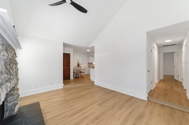 unfurnished living room featuring high vaulted ceiling, light wood-type flooring, a ceiling fan, and baseboards