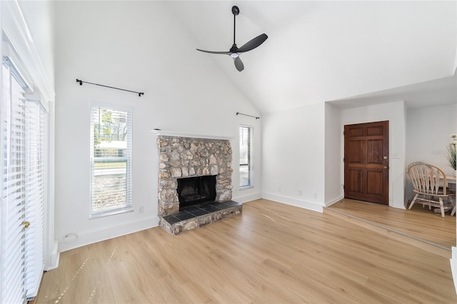 unfurnished living room with high vaulted ceiling, a fireplace, a ceiling fan, baseboards, and light wood finished floors