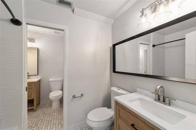 bathroom with a shower, visible vents, toilet, vanity, and baseboards