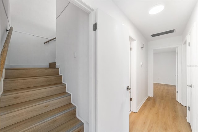 stairs with baseboards, visible vents, and wood finished floors