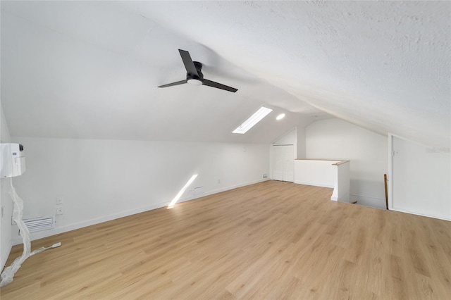 bonus room featuring a textured ceiling, a ceiling fan, baseboards, vaulted ceiling, and light wood-style floors