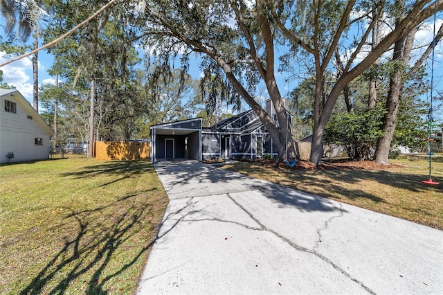 view of front of house featuring glass enclosure, aphalt driveway, fence, a carport, and a front lawn