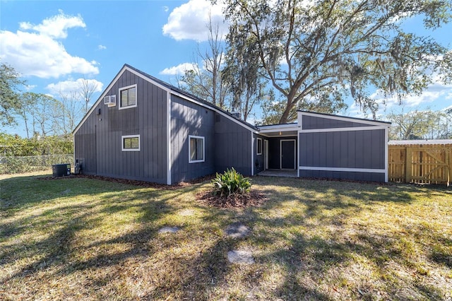 back of house featuring a lawn, cooling unit, and fence