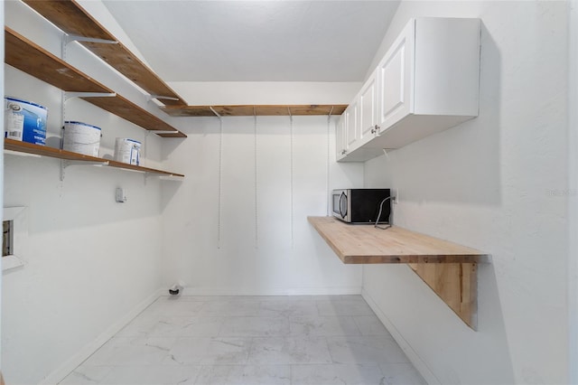 washroom with marble finish floor, cabinet space, and baseboards