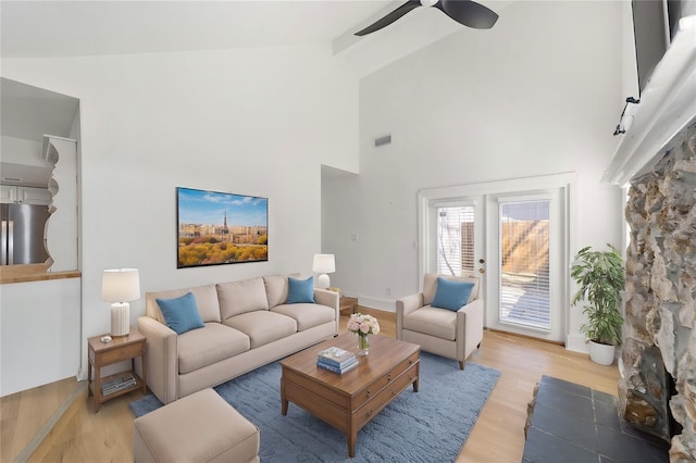 living room with high vaulted ceiling, visible vents, baseboards, a ceiling fan, and light wood-type flooring