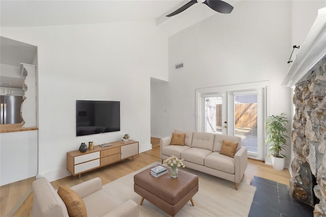 living area featuring a ceiling fan, visible vents, high vaulted ceiling, and light wood finished floors