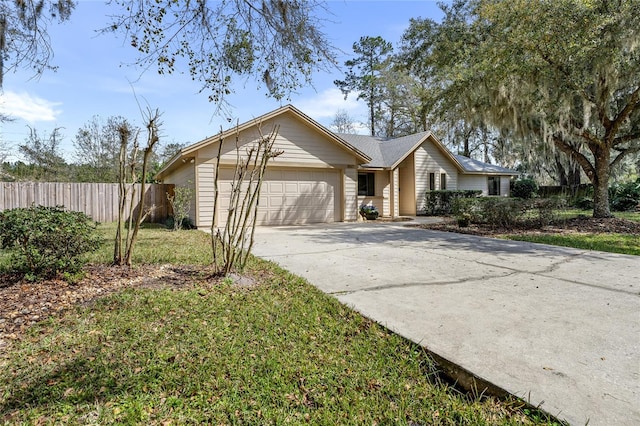 ranch-style home with concrete driveway, a front lawn, an attached garage, and fence