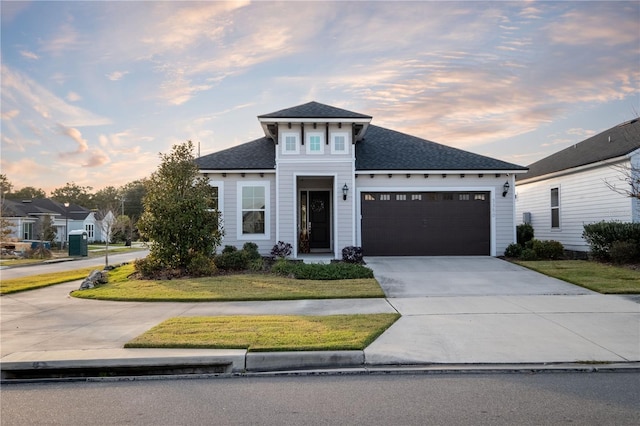 view of front of home featuring a front yard, roof with shingles, driveway, and an attached garage