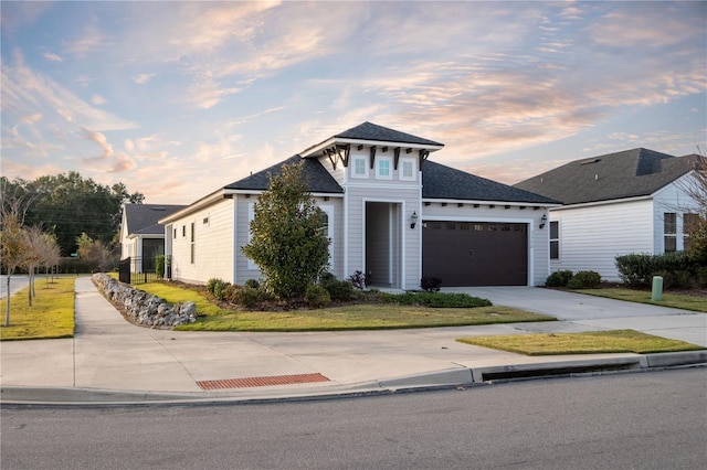 view of front facade with a garage, concrete driveway, and a yard