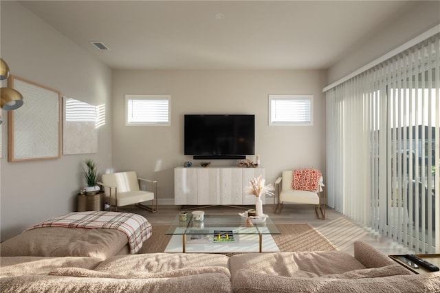 living area with a wealth of natural light, visible vents, and wood finished floors