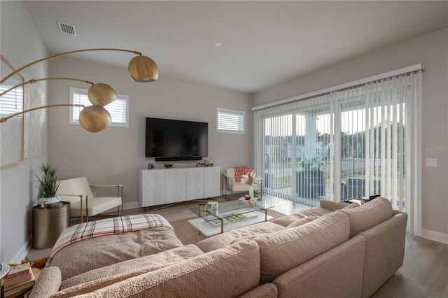 living area featuring baseboards, plenty of natural light, visible vents, and wood finished floors