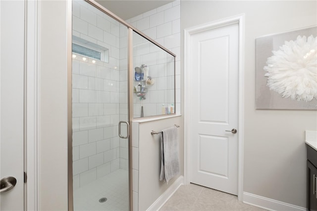 full bathroom featuring a stall shower, tile patterned flooring, vanity, and baseboards