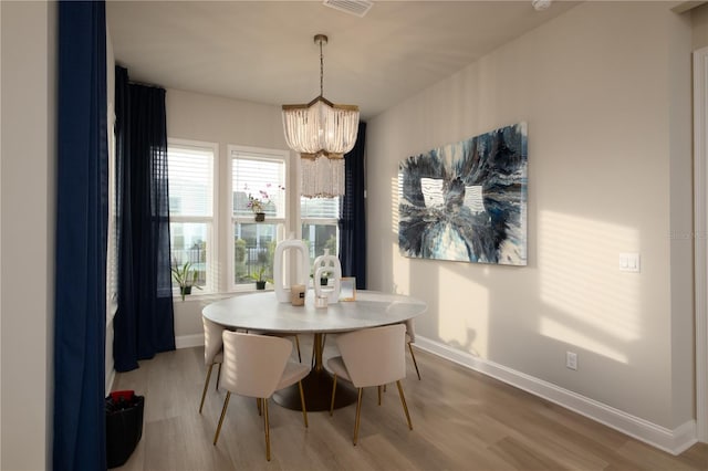 dining room with light wood finished floors, visible vents, baseboards, and a notable chandelier