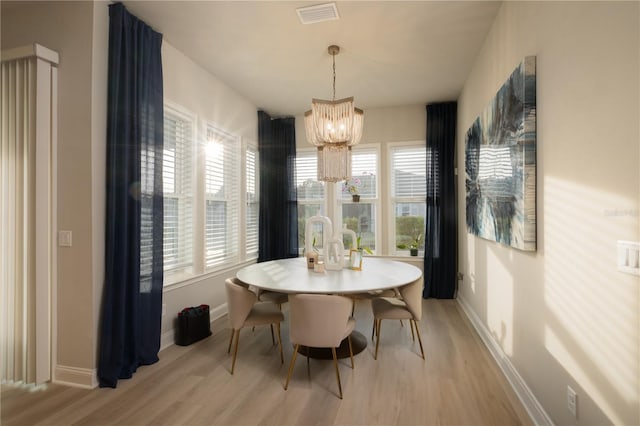 dining area with a chandelier, light wood-type flooring, visible vents, and baseboards