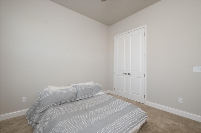 carpeted bedroom featuring baseboards and a closet