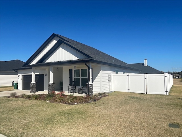 rear view of property featuring a yard, board and batten siding, a gate, a garage, and driveway