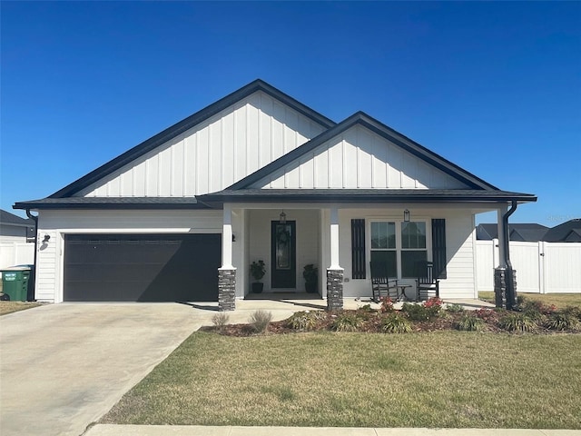 view of front of home with an attached garage, a porch, concrete driveway, and a front yard