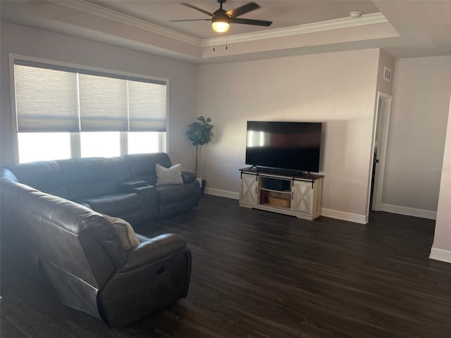 living room featuring dark wood-style floors, baseboards, ornamental molding, and a raised ceiling