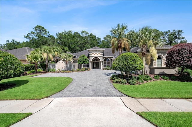 mediterranean / spanish home with stucco siding, decorative driveway, and a front lawn