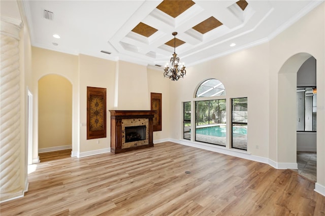 unfurnished living room with light wood-type flooring, visible vents, arched walkways, baseboards, and a towering ceiling