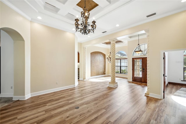 foyer entrance featuring wood finished floors, coffered ceiling, ornate columns, arched walkways, and a notable chandelier