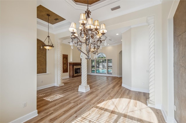 interior space with visible vents, ornamental molding, a fireplace, wood finished floors, and arched walkways