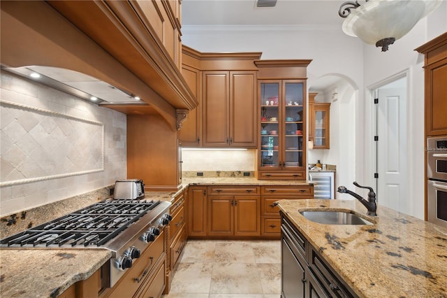 kitchen featuring premium range hood, stainless steel gas cooktop, arched walkways, a sink, and crown molding