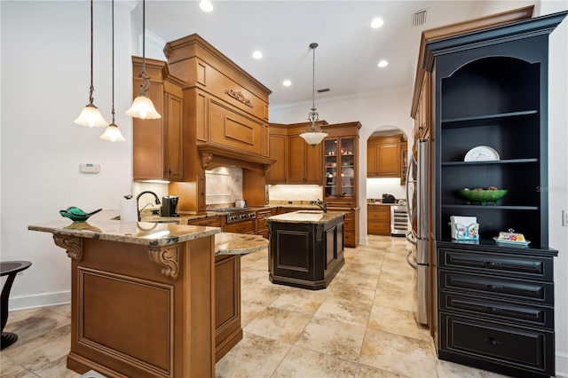 kitchen featuring light stone countertops, a peninsula, arched walkways, a sink, and brown cabinets